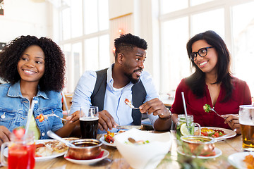 Image showing happy friends eating and talking at restaurant