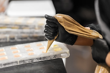 Image showing confectioner filling mold by cream at pastry shop