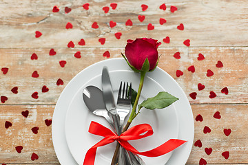 Image showing close up of red rose flower on set of dishes