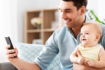 Image showing father with baby daughter using smartphone at home