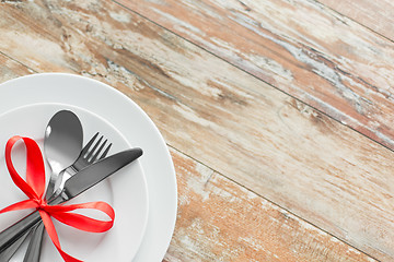 Image showing cutlery tied with red ribbon on set of plates