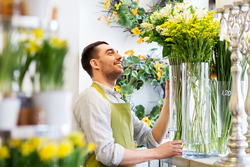 Image showing happy florist man setting flowers at flower shop