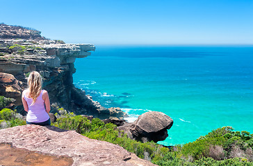 Image showing Female sitting on cliffs by the ocean