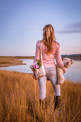 Image showing Woman standing in long dry grasses by lake