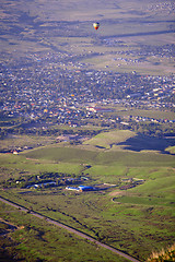 Image showing Hot air balloon above the green field and villages