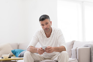 Image showing young man using a mobile phone  at home