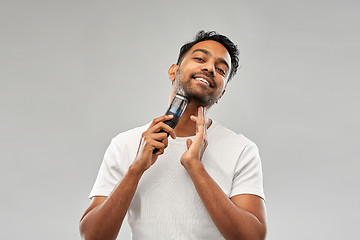 Image showing smiling indian man shaving beard with trimmer