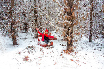 Image showing Woman on a couch among the snow covered pine forest in winter