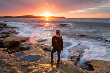 Image showing Sunflare kissing the shoulder of a woman watching sunrise by the