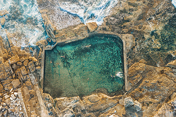 Image showing Swimmers refresh themselves in coastal rock pool early morning.