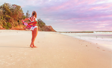 Image showing Woman on beach with beach towel flapping behind her