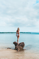 Image showing Woman in bikini standing on a rock surrounded by the ocean