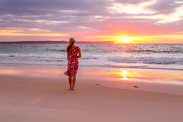 Image showing Woman standing on the wet sand of the beach watching sunrise