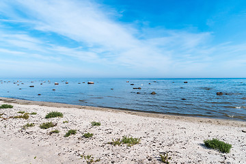 Image showing Summer view by a sand beach with rocks in the water 