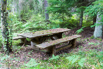 Image showing Old weathered furniture by a resting place in a forest