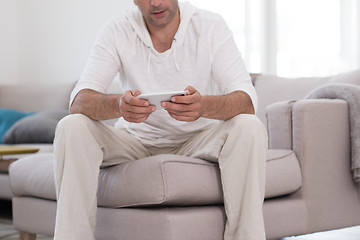 Image showing young man using a mobile phone  at home