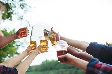 Image showing Bottles of beer in people\'s hands on blue sky background