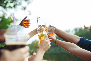 Image showing Bottles of beer in people\'s hands on blue sky background