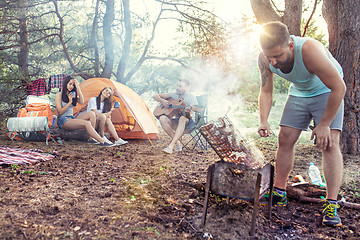 Image showing Party, camping of men and women group at forest. They relaxing, singing a song and cooking barbecue