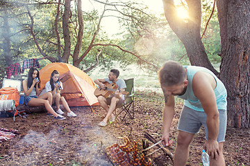 Image showing Party, camping of men and women group at forest. They relaxing, singing a song and cooking barbecue