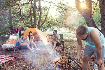 Image showing Party, camping of men and women group at forest. They relaxing, singing a song and cooking barbecue