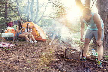 Image showing Party, camping of men and women group at forest. They relaxing, singing a song and cooking barbecue