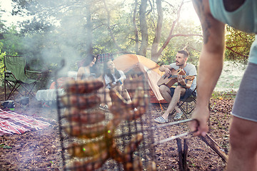 Image showing Party, camping of men and women group at forest. They relaxing, singing a song and cooking barbecue