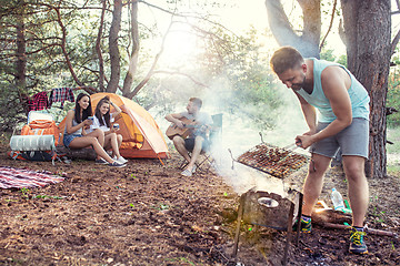 Image showing Party, camping of men and women group at forest. They relaxing, singing a song and cooking barbecue