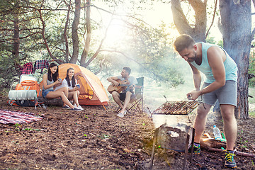 Image showing Party, camping of men and women group at forest. They relaxing, singing a song and cooking barbecue