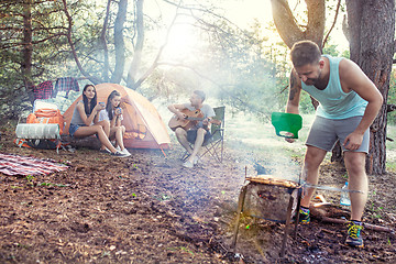 Image showing Party, camping of men and women group at forest. They relaxing, singing a song and cooking barbecue