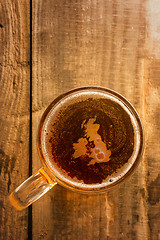 Image showing English beer concept, Great Britain silhouette on foam in beer glass on wooden table.