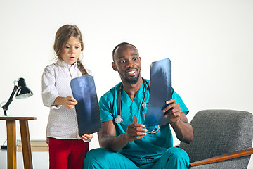 Image showing Young african male pediatrician explaining X-ray to child