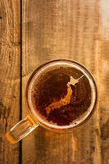 Image showing japanese beer concept, silhouette on foam in beer glass on wooden table.