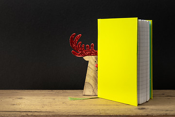 Image showing a yellow green note book with hidden reindeer on a wooden table