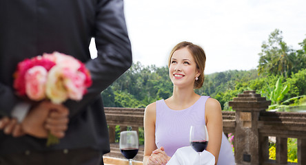 Image showing woman looking at man with flowers at restaurant