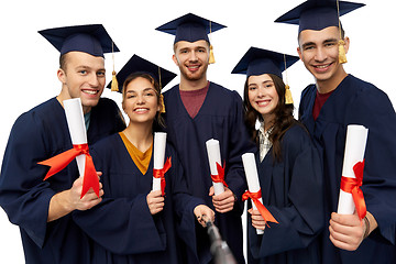 Image showing happy graduates with diplomas taking selfie