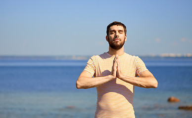 Image showing man meditating outdoors over sea