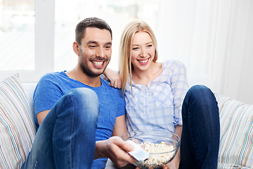 Image showing happy couple with popcorn watching tv at home
