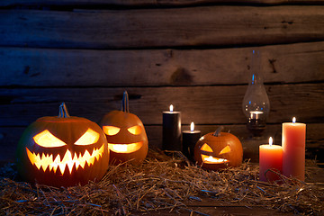 Image showing Jack-O-Lantern Halloween pumpkins on rough wooden planks with candles