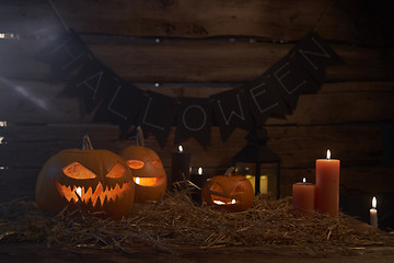 Image showing Jack-O-Lantern Halloween pumpkins on rough wooden planks with candles