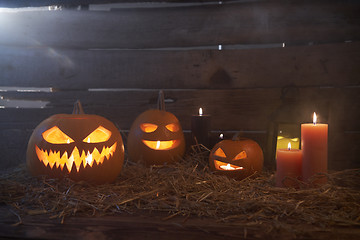 Image showing Jack-O-Lantern Halloween pumpkins on rough wooden planks with candles