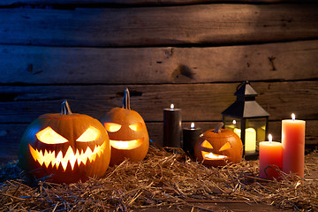 Image showing Jack-O-Lantern Halloween pumpkins on rough wooden planks with candles