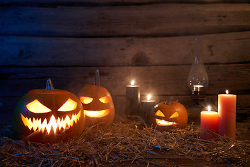 Image showing Jack-O-Lantern Halloween pumpkins on rough wooden planks with candles