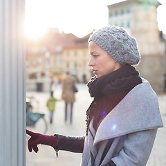 Image showing Casual woman buying public transport tickets on city urban vedning machine on cold winter day.