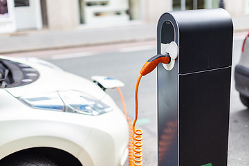 Image showing Power supply for electric car charging. Electric car charging station. Close up of the power supply plugged into an electric car being charged.