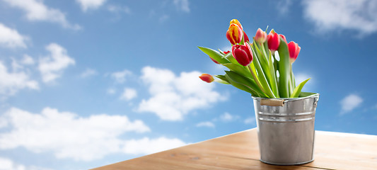 Image showing red tulip flowers in tin bucket on table