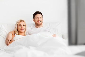 Image showing happy couple lying in bed at home and watching tv