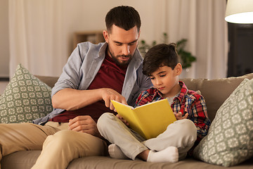 Image showing father and son reading book sofa at home