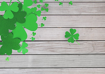 Image showing green paper shamrocks on wooden background