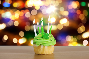 Image showing green cupcake with six burning candles on table